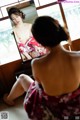 A woman in a kimono looking at herself in the mirror.