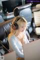 A woman sitting at a desk with a laptop and headphones on.