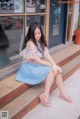 A woman sitting on the steps of a building wearing a blue dress.