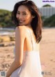 A woman in a white dress standing on a beach.