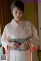 A woman in a pink kimono is posing for a picture.