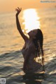 A woman standing in the ocean with her arms outstretched.