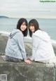 A couple of women sitting next to each other on a wall.