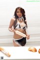 A woman in lingerie holding a rolling pin and a loaf of bread.