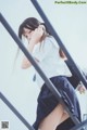 A young woman in a school uniform leaning against a railing.