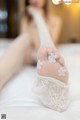 A woman laying on a bed with her feet up in white socks.