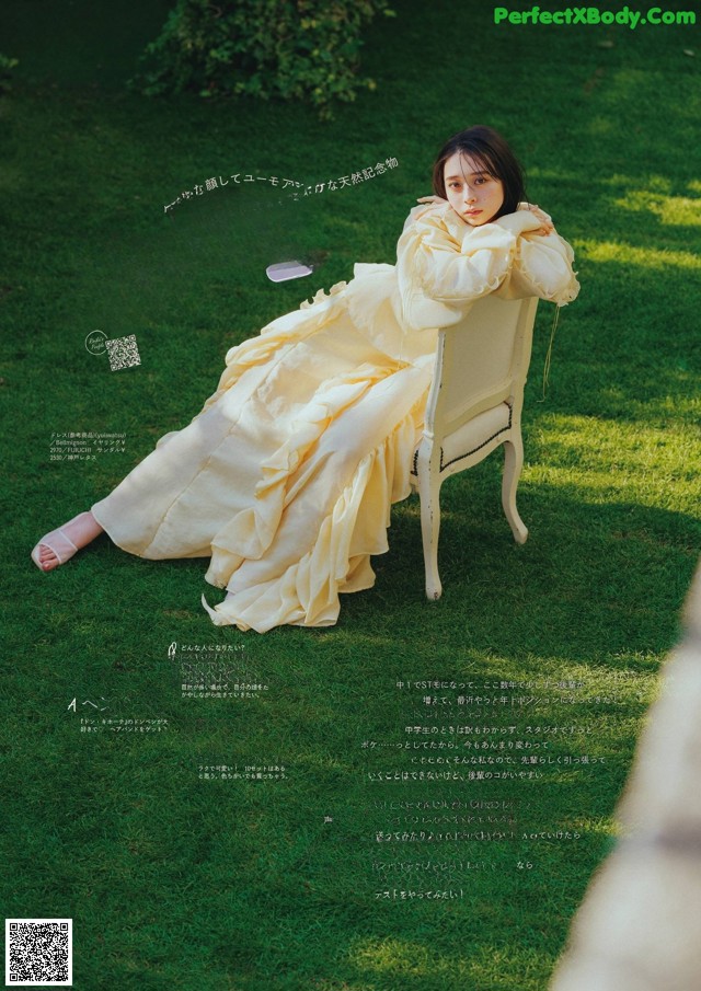 A woman in a yellow dress sitting on a white chair.