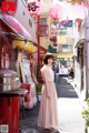 A woman in a pink dress standing in an alleyway.