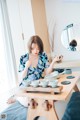 A woman sitting at a table with bowls and cups on it.