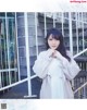 A woman in a white dress standing next to a metal fence.