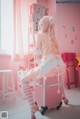 A woman sitting on top of a pink suitcase.