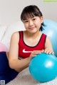 A young girl sitting on the floor holding a blue ball.