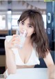 A woman sitting at a table drinking a glass of water.